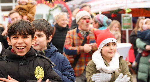 Weihnachtsmarkt. Fröhliche Kinder im Vordergrund.